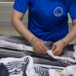 Worker inspecting a black-and-white fleece blanket during production